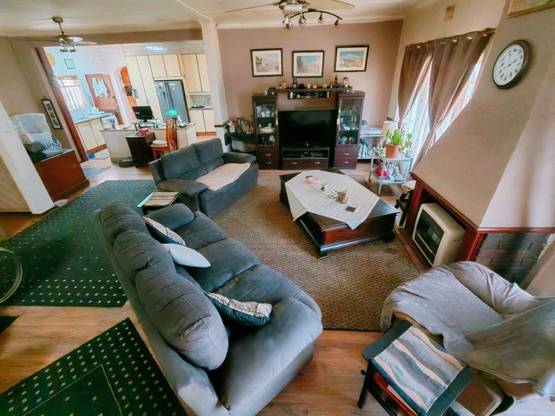 Open-plan living area featuring a built-in fireplace, ceiling fans, and an adjacent kitchen with functional cabinetry and laminate flooring.