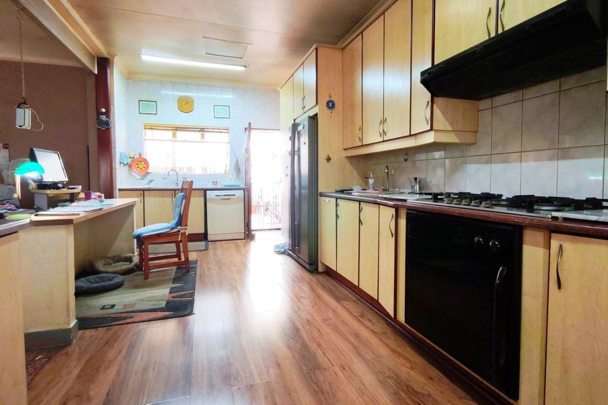 Functional kitchen featuring light wood cabinetry, gas hob, built-in oven, extractor fan, and laminate flooring with a dedicated prep area.