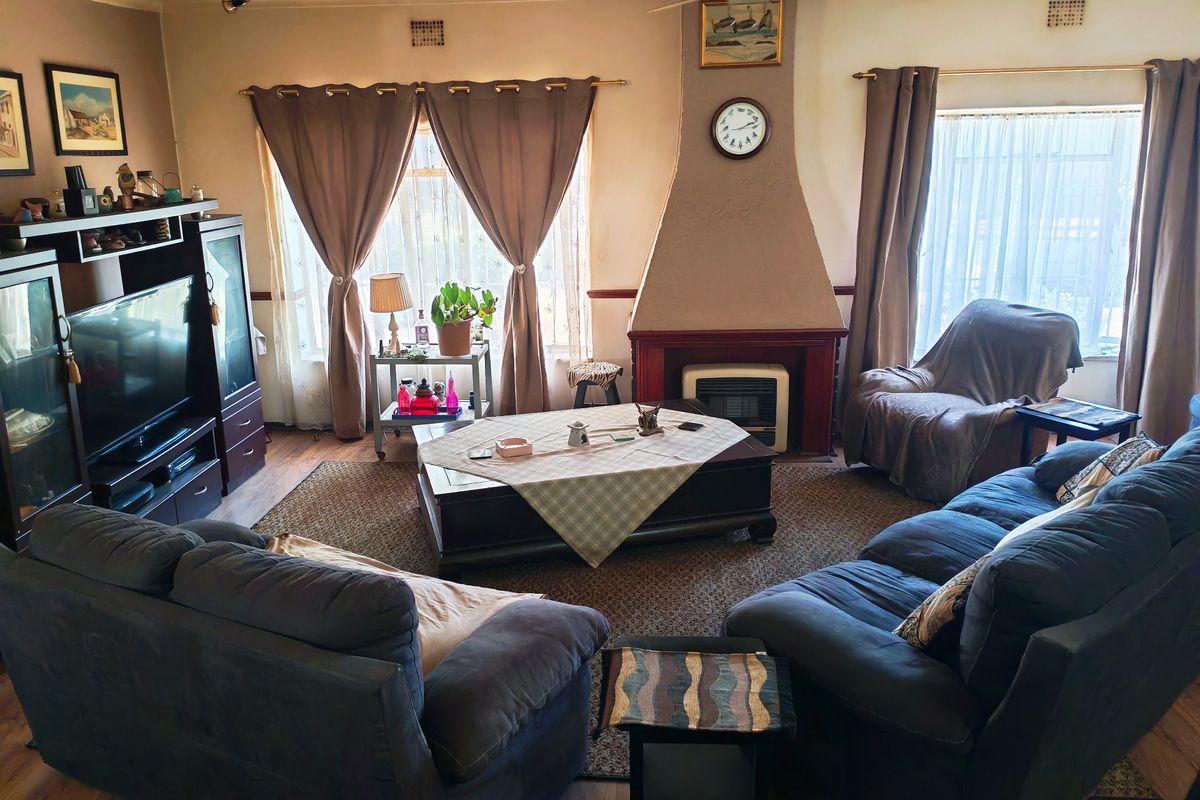 A traditional living room featuring a central fireplace, ceiling fan, and laminate flooring, offering a comfortable and functional space.