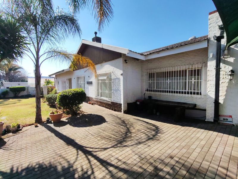 Rear exterior view of the house featuring a paved patio area, security bars on windows, and a textured facade.