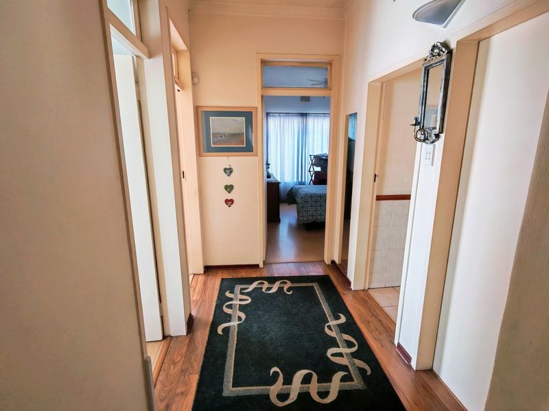 A well-lit interior hallway featuring laminate flooring, connecting multiple rooms with traditional architraves and transom window detailing.