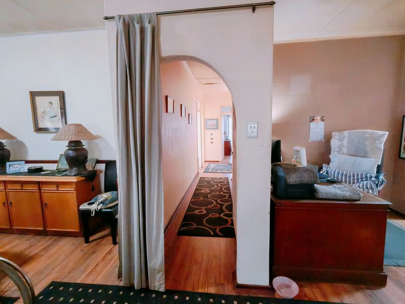 A central hallway featuring an arched entryway, hardwood flooring, and neutral wall tones connecting the living spaces.