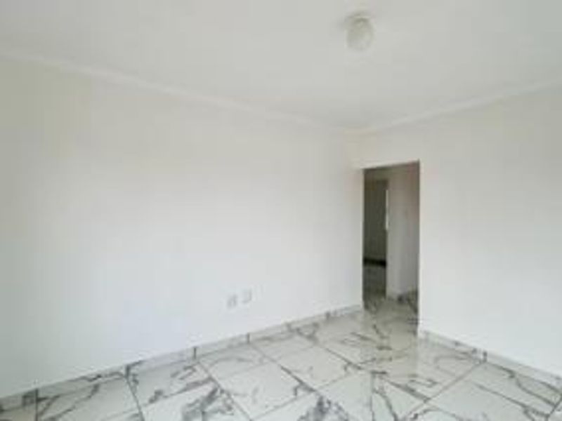 An empty living area featuring modern marble-look floor tiles, neutral white walls, and a simple ceiling light fixture.