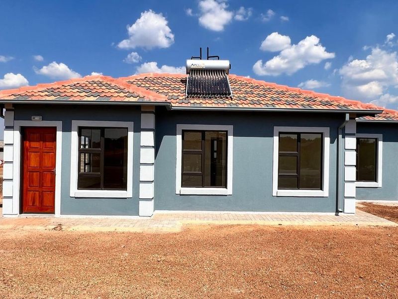 A modern single-story residential home featuring a tiled roof, solar water heating system, and neat exterior finishes with a paved entrance area.
