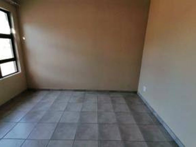 An empty bedroom featuring neutral wall tones and tiled flooring, providing a blank canvas for personalization.