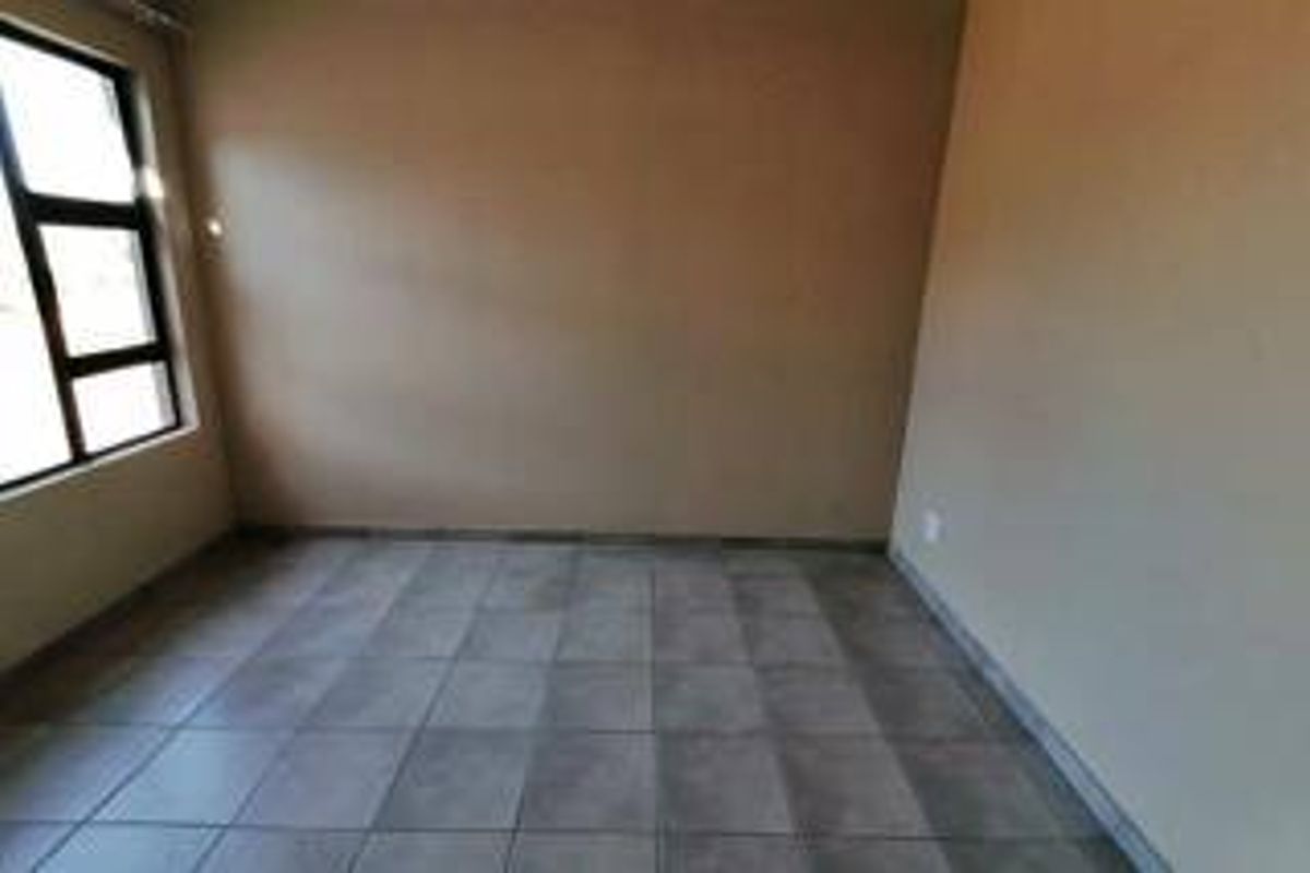 An empty bedroom featuring neutral wall tones and tiled flooring, providing a blank canvas for personalization.