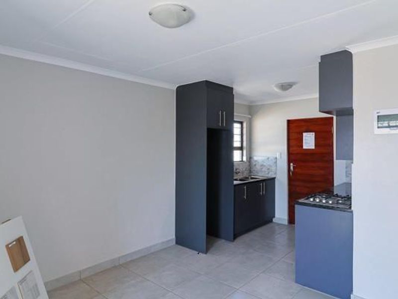 A clean, modern kitchen featuring dark grey cabinetry, a built-in gas hob, and tiled flooring in an open-plan layout.