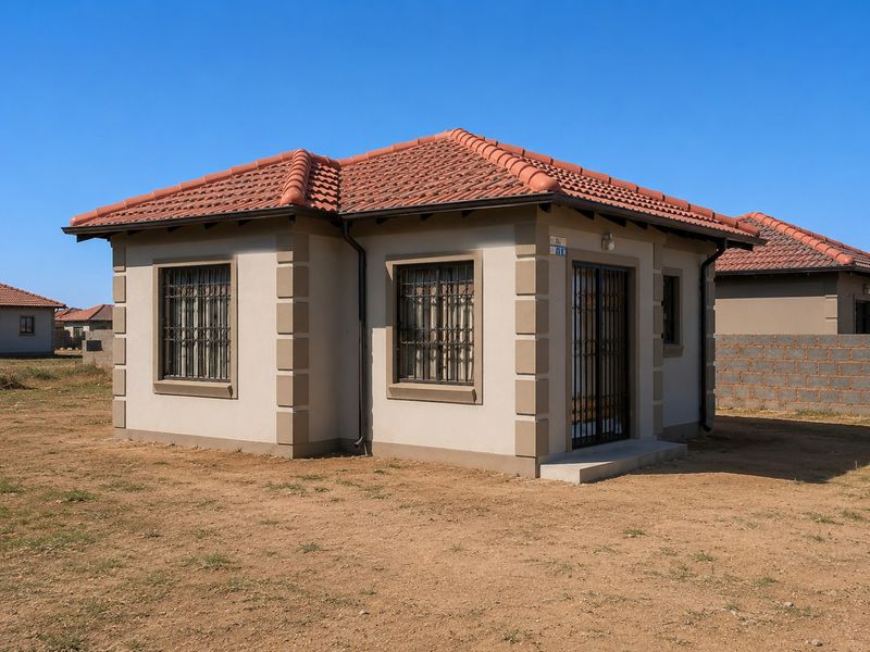 A well-maintained single-story detached house featuring terracotta roof tiles, quoined corner detailing, and security bars on windows, set on an open plot.