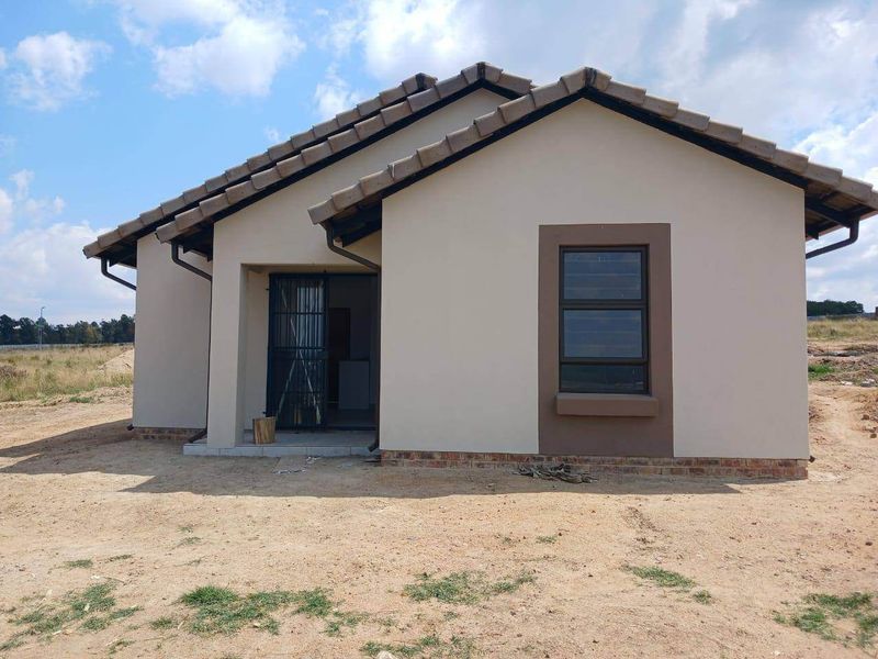 A modern single-story residential house featuring a tiled roof, neutral exterior paint, and aluminium window frames, set on an unlandscaped plot.