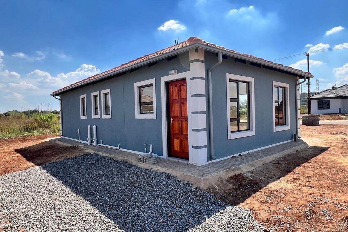 A modern single-story house exterior featuring grey rendered walls, white trim detailing, a tiled roof, and a timber entrance door with paved surrounds.