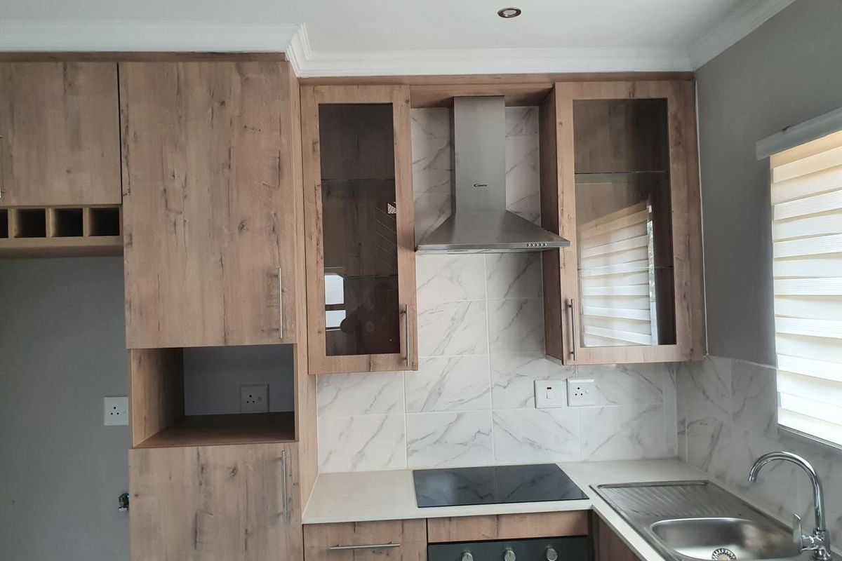 Modern kitchen featuring wood-look cabinetry, marble-effect tiled backsplash, integrated stainless steel appliances, and a double bowl sink with a contemporary mixer tap.
