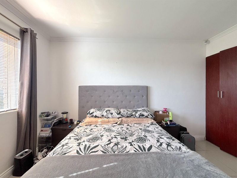 A functional bedroom featuring tiled flooring, a built-in wardrobe, and venetian blinds, providing a neutral base for personalization.