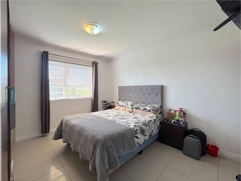A functional bedroom featuring tiled flooring, a central ceiling light, and a window fitted with blinds.