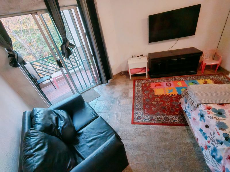 Living room area featuring tiled flooring and a sliding glass door providing direct access to an outdoor balcony.