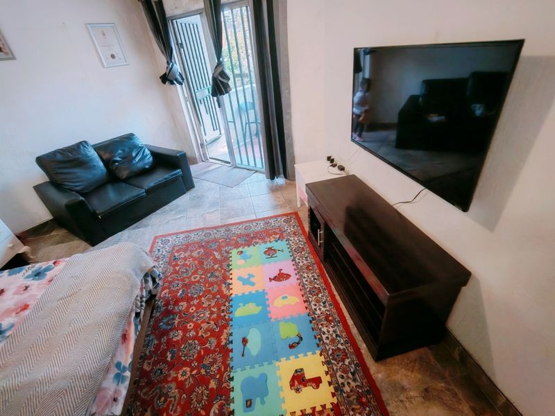 A compact living room featuring tiled flooring and a sliding glass door providing access to an outdoor area.