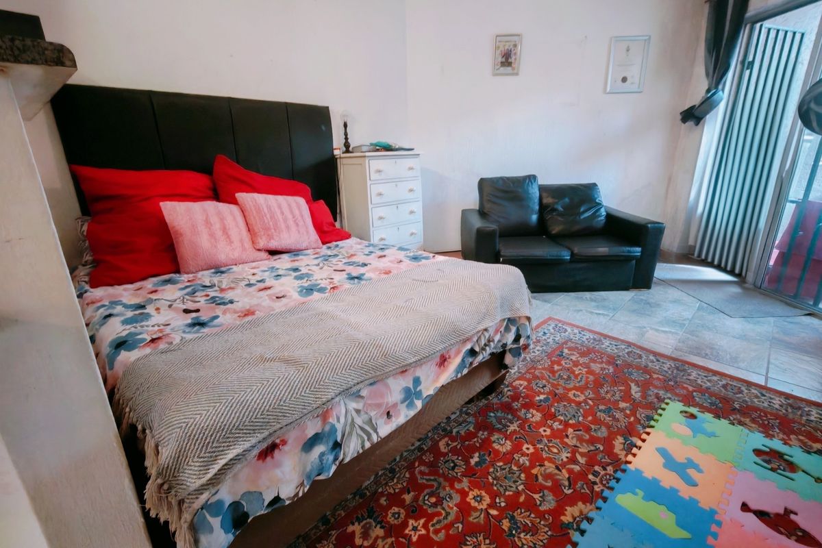 Spacious bedroom featuring tiled flooring and direct access to an outdoor area through a sliding glass door.