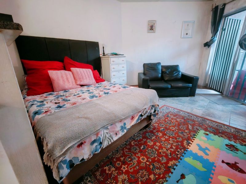 Spacious bedroom featuring tiled flooring and direct access to an outdoor area through a sliding glass door.