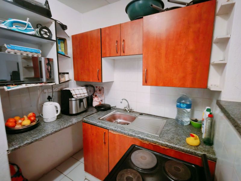 Compact kitchen featuring wood-look laminate cabinetry, granite countertops, a stainless steel sink, and a built-in electric stove.