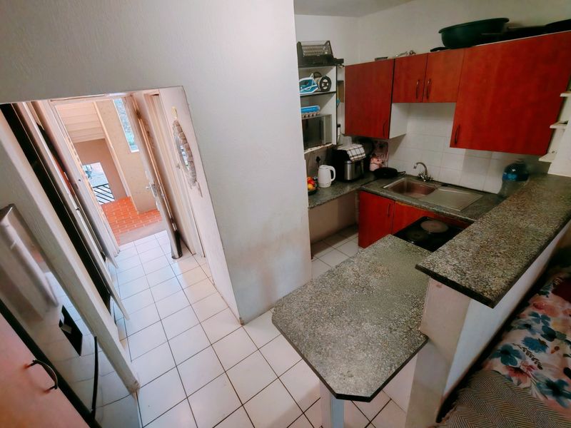 Compact kitchen featuring laminate countertops, built-in cabinetry, and an electric hob, with direct access to the apartment entrance hallway.