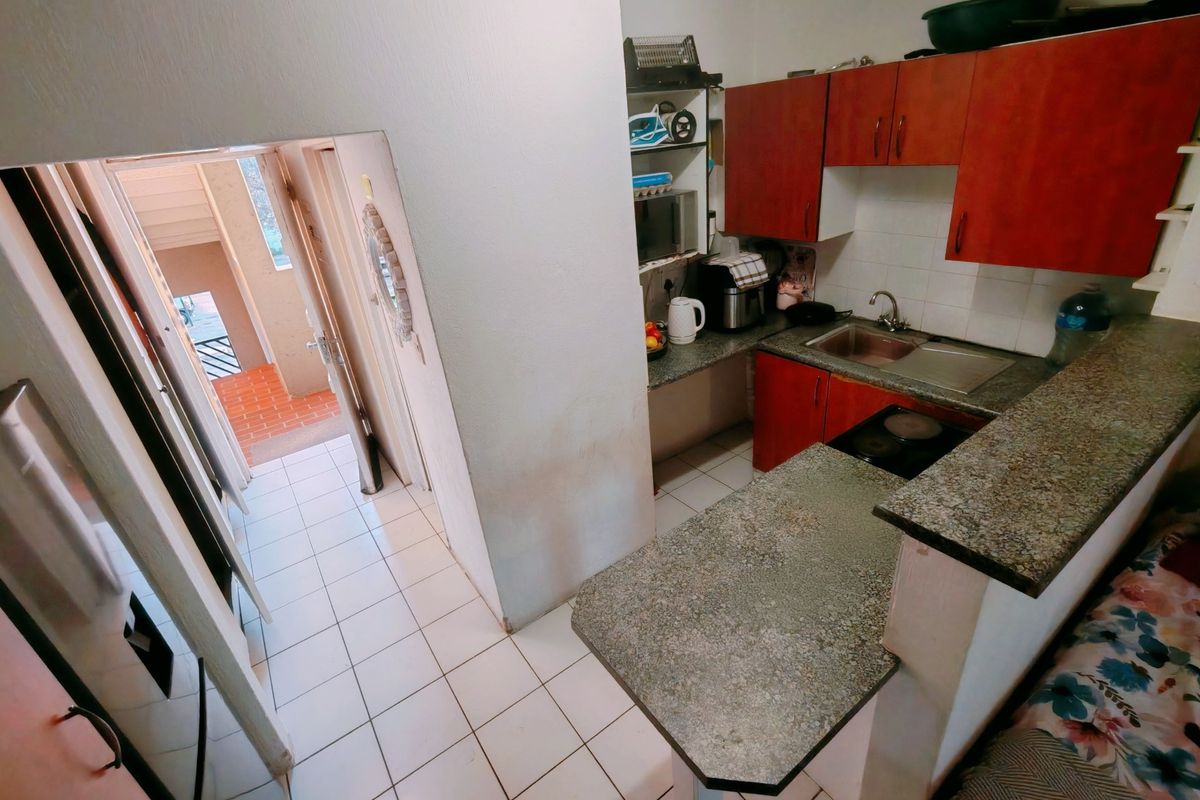 Compact kitchen featuring laminate countertops, built-in cabinetry, and an electric hob, with direct access to the apartment entrance hallway.