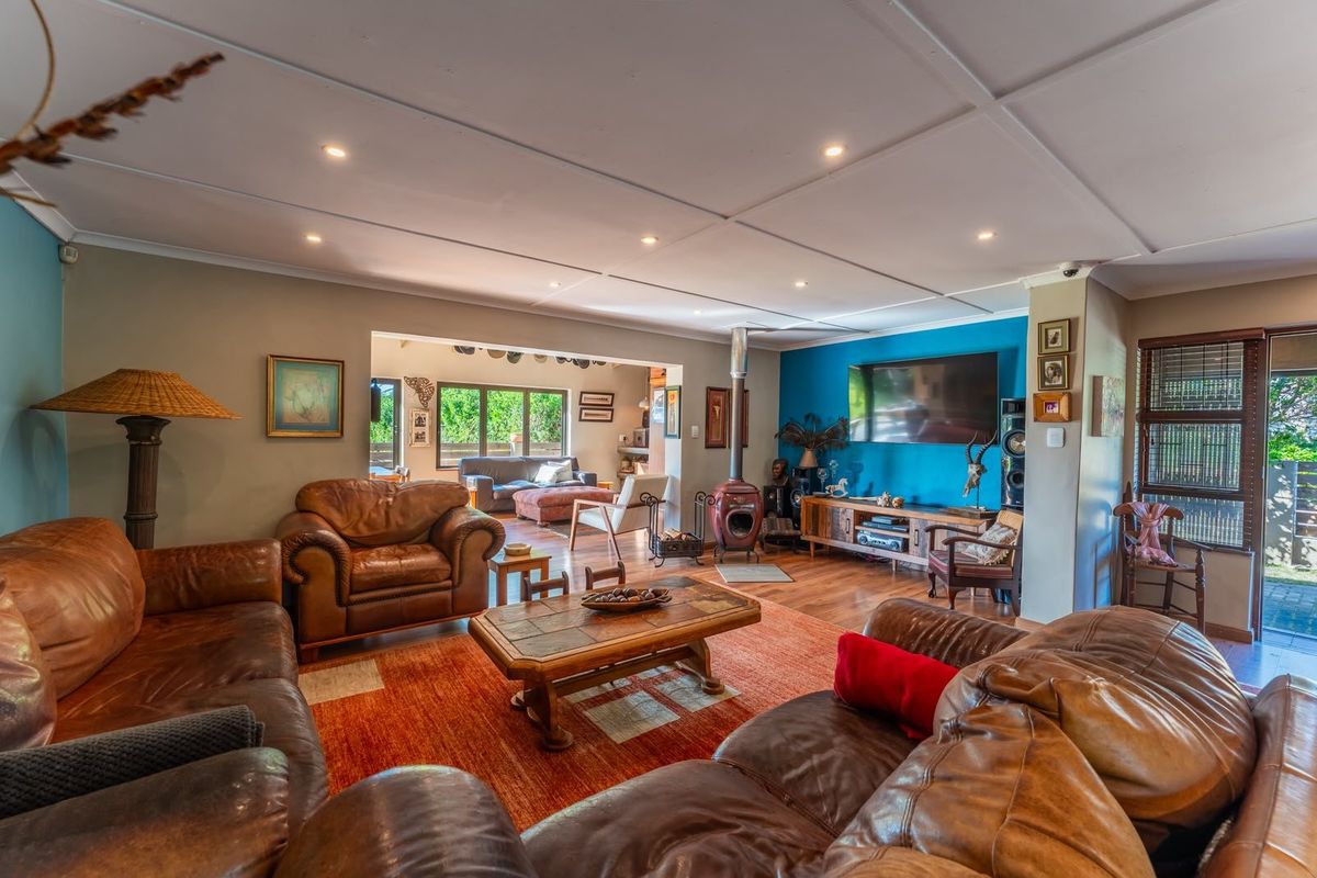 Spacious living room featuring a freestanding fireplace, recessed downlighting, and hardwood flooring, with an open-plan flow to the adjacent living area.