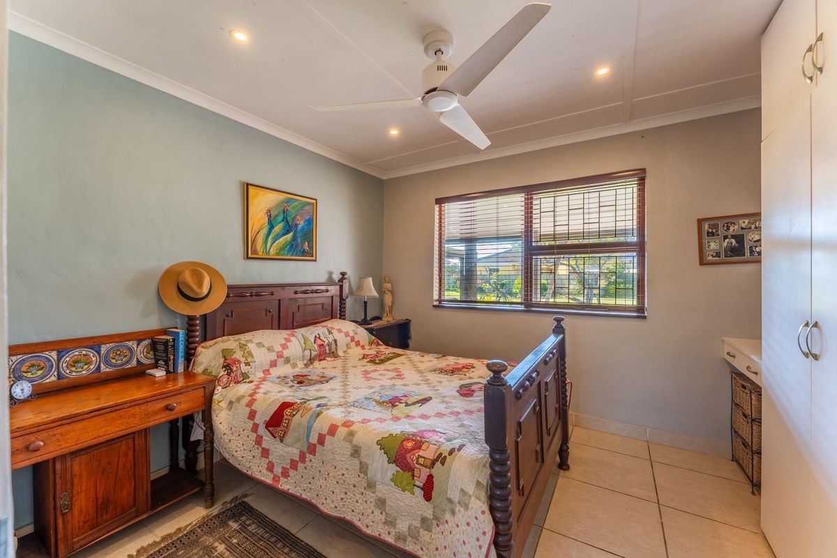 A well-lit bedroom featuring tiled flooring, a ceiling fan, recessed lighting, and a built-in wardrobe with ample storage space.