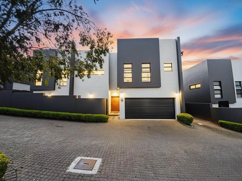 Modern double-story residential facade featuring a sleek grey and white exterior, paved driveway, and integrated double garage.