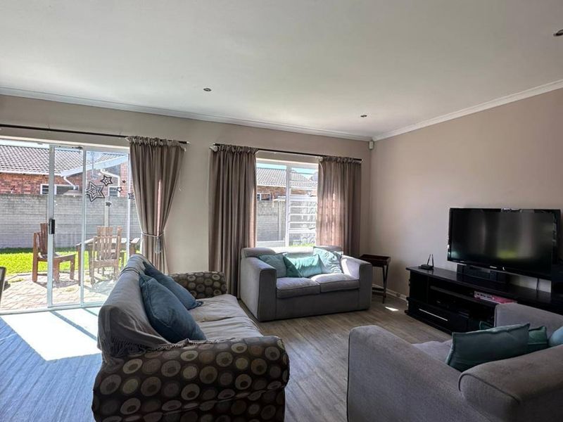 Spacious living room featuring laminate flooring, recessed downlights, and large sliding glass doors providing direct access to the rear patio area.