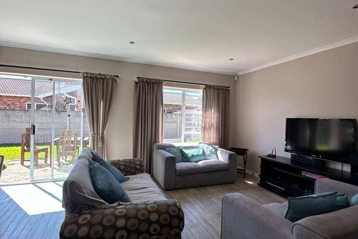Spacious living room featuring laminate flooring, recessed downlights, and large sliding glass doors providing direct access to the rear patio area.