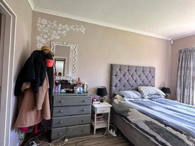 A bedroom featuring laminate flooring and decorative coving, providing a functional space with neutral wall tones.