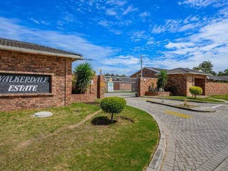 The entrance to Walkerdale Estate featuring a brick facade, secure gated access, and a well-maintained paved driveway.