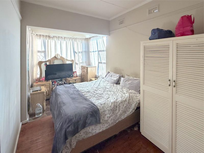 A bedroom featuring a built-in wardrobe, air conditioning vent, and a bay window that provides natural light.