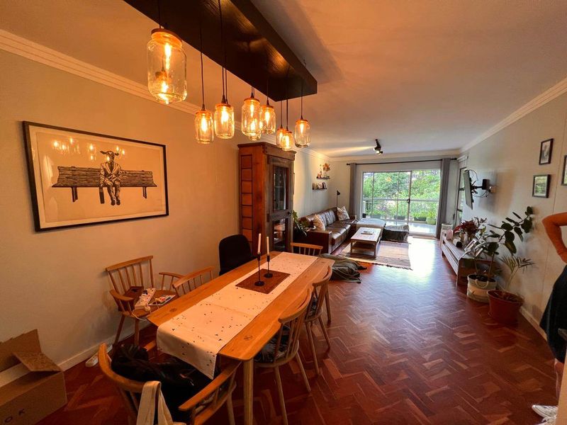 Open-plan living and dining area featuring classic herringbone parquet flooring, coved ceilings, and direct access to a private balcony through sliding glass doors.
