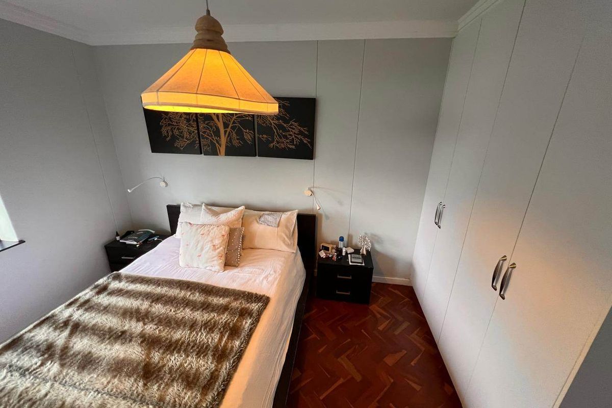 A cozy bedroom featuring classic parquet flooring, ample built-in cupboard storage, and decorative coving.