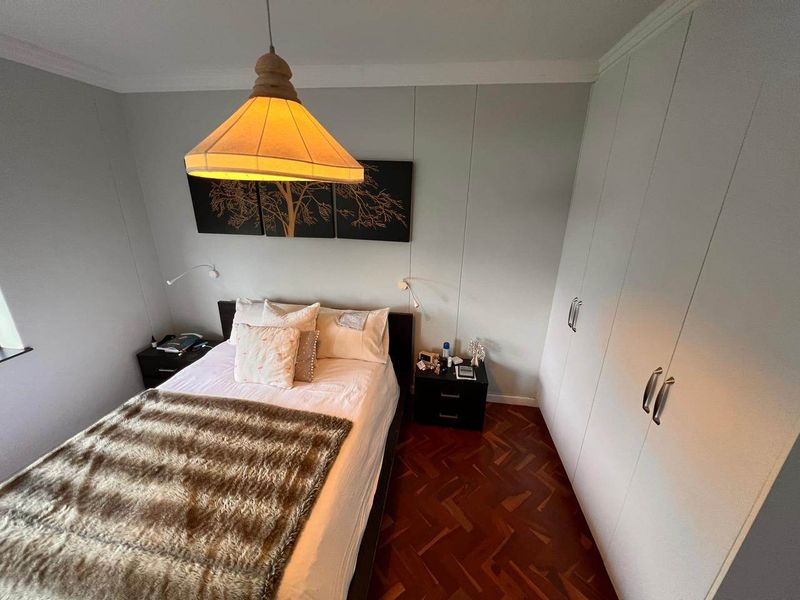 A cozy bedroom featuring classic parquet flooring, ample built-in cupboard storage, and decorative coving.