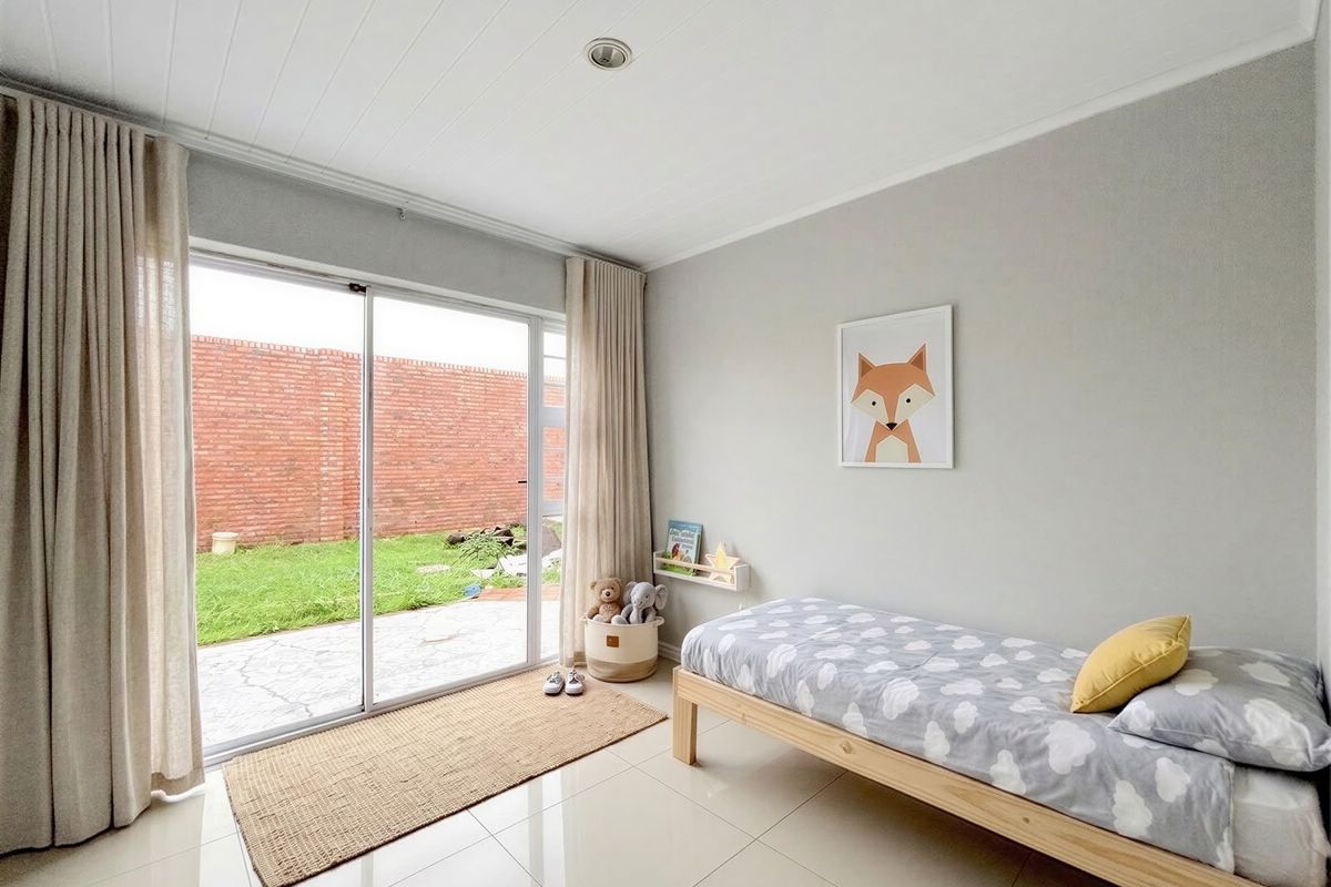 A bright bedroom featuring tiled flooring, recessed lighting, and a large sliding glass door providing direct access to the rear garden.
