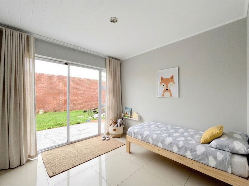 A bright bedroom featuring tiled flooring, recessed lighting, and a large sliding glass door providing direct access to the rear garden.
