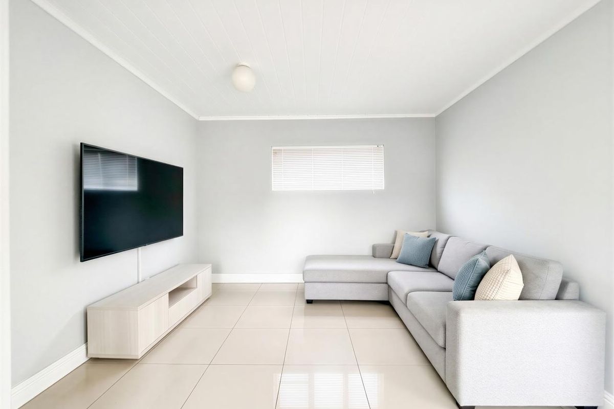 A bright and modern living room featuring neutral tiled flooring, a tongue and groove ceiling, and clean finishes.