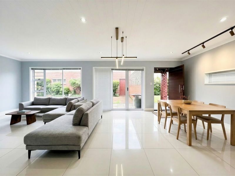 Spacious open-plan living and dining area featuring polished tiled floors, modern lighting, and direct access to the rear garden through sliding glass doors.