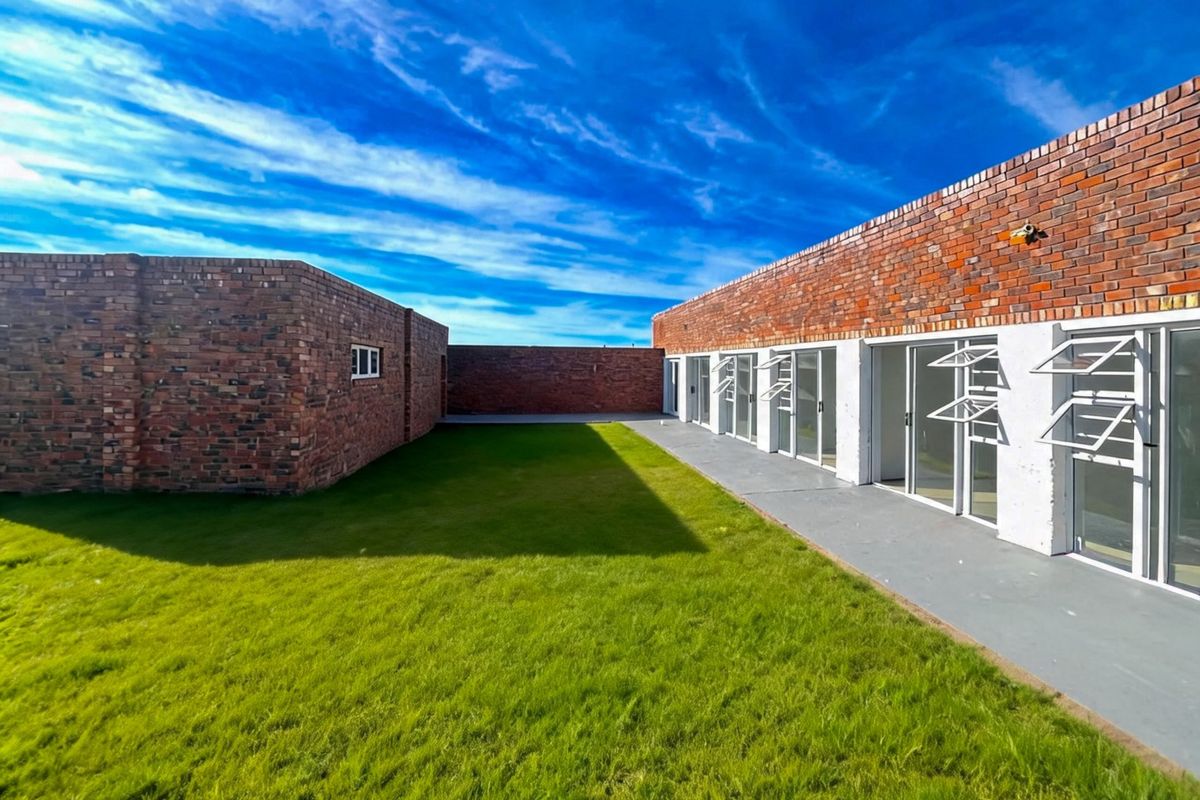 Rear exterior view featuring exposed brick walls, a concrete patio, and multiple sliding glass doors leading into the property.