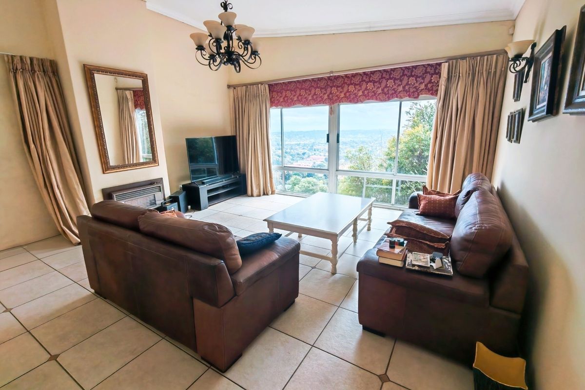 Spacious living room featuring large sliding windows with panoramic views, tiled flooring, and a built-in fireplace.