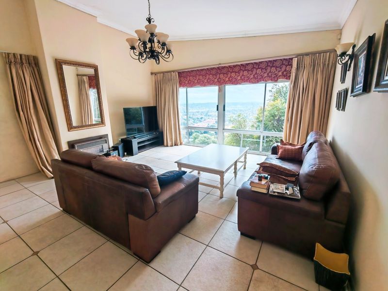 Spacious living room featuring large sliding windows with panoramic views, tiled flooring, and a built-in fireplace.