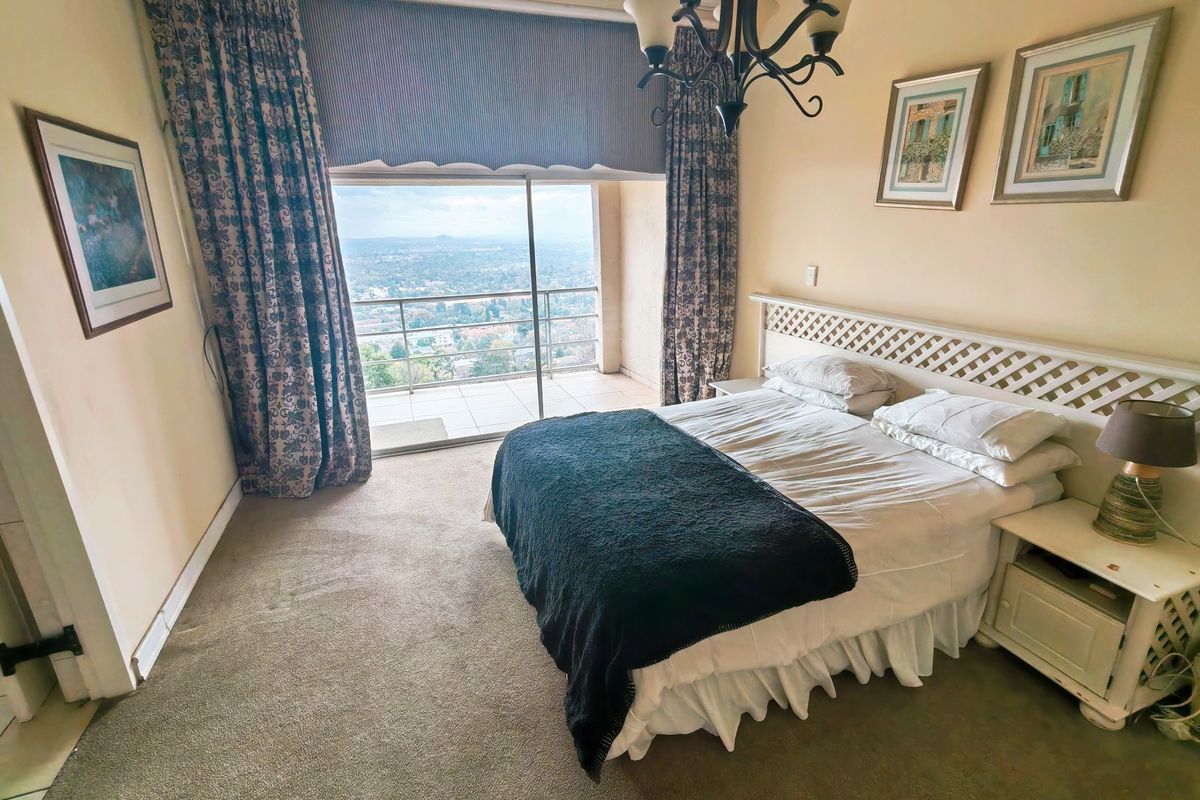 A bedroom featuring carpeted flooring and a sliding glass door that opens onto a balcony with expansive elevated views.