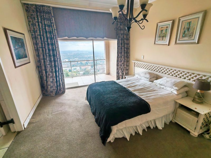 A bedroom featuring carpeted flooring and a sliding glass door that opens onto a balcony with expansive elevated views.