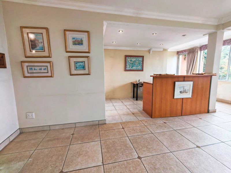 Spacious living area featuring ceramic tiled flooring, recessed downlighting, and a built-in wooden counter, offering a versatile layout for various living arrangements.