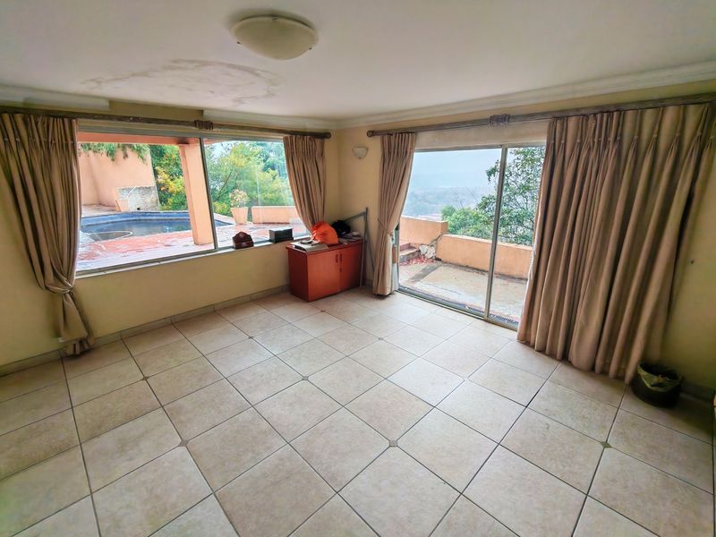 Spacious living area featuring tiled flooring and large sliding glass doors providing access to an outdoor patio and pool area.