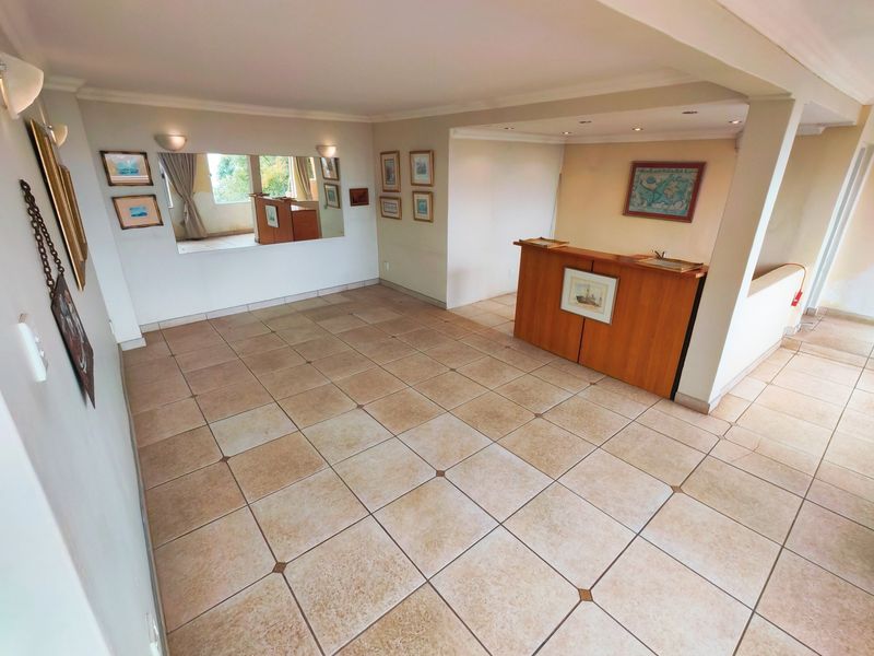 Spacious living area featuring ceramic tile flooring, a built-in bar, and recessed lighting, offering a versatile layout for entertaining.