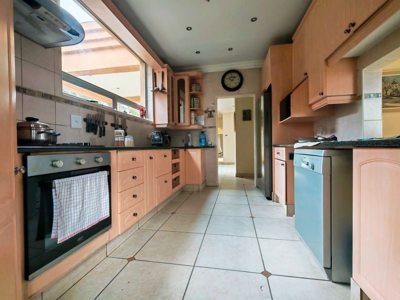 A functional kitchen featuring light wood cabinetry, granite countertops, built-in oven, and tiled flooring, offering a practical layout with ample storage space.