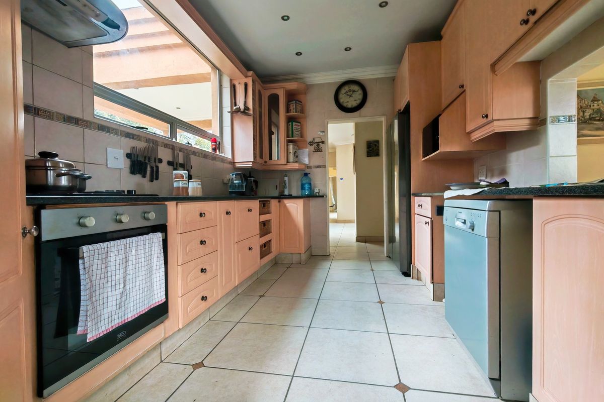 A functional kitchen featuring light wood cabinetry, granite countertops, built-in oven, and tiled flooring, offering a practical layout with ample storage space.