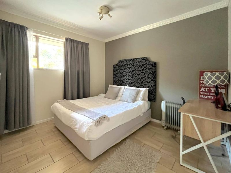 A bedroom featuring tiled flooring, neutral wall tones, and decorative ceiling cornicing, providing a functional and comfortable living space.